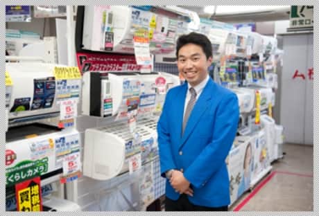 家電が並ぶ店内で笑顔でこちらをむく男性従業員